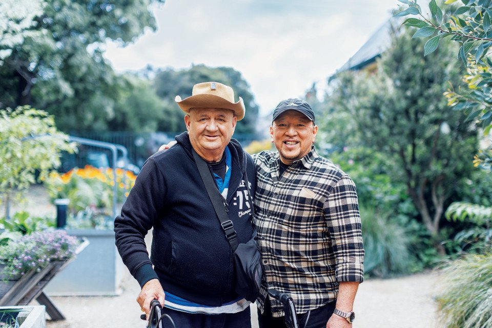 Older man in hat standing next to younger man in cap